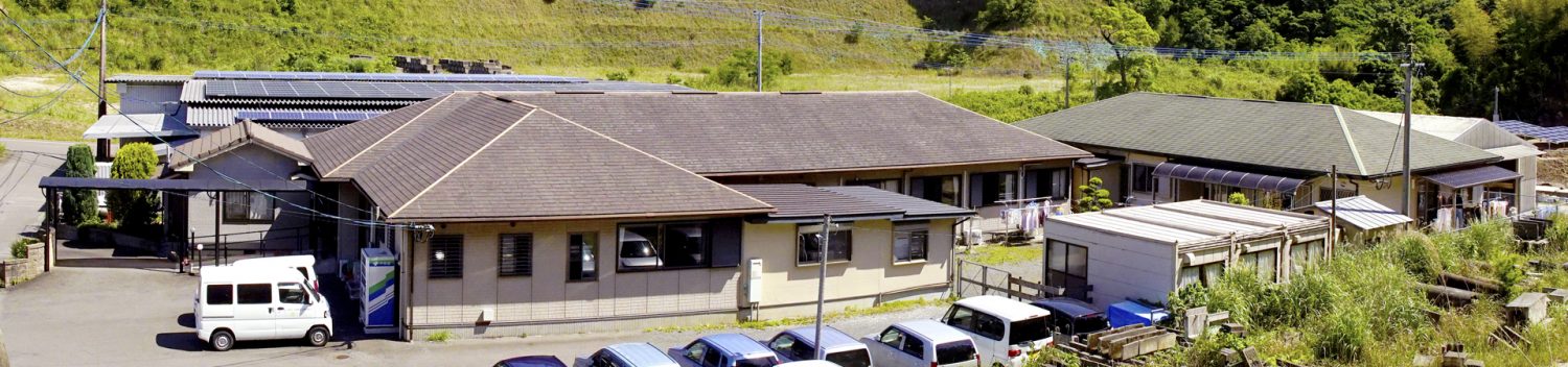 介護施設の建物外観。駐車場と周辺環境を含む全体像。